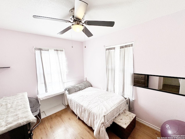 133 Rio Grande St, Uvalde, TX 78801 - bedroom with multiple windows, light wood-style floors, a ceiling fan, and baseboards