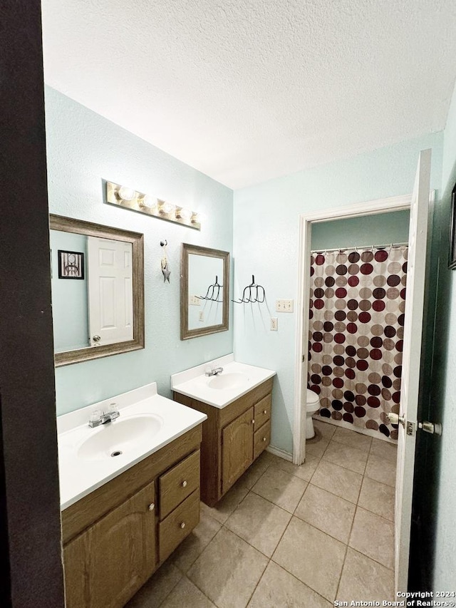 133 Rio Grande St, Uvalde, TX 78801 - full bathroom with two vanities, toilet, tile patterned floors, a textured ceiling, and a shower with shower curtain