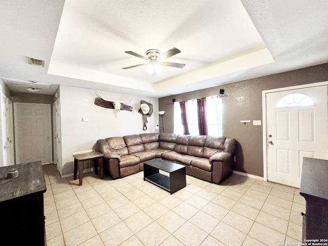 living room featuring ceiling fan, a raised ceiling, and light tile patterned flooring