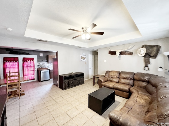 living room with ceiling fan, light tile patterned flooring, and a raised ceiling