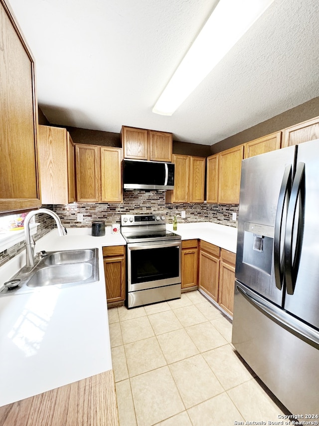 kitchen featuring light tile patterned flooring, sink, a textured ceiling, backsplash, and stainless steel appliances