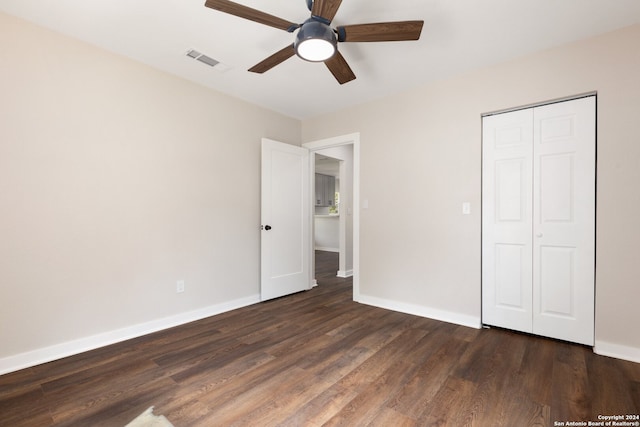 unfurnished bedroom with dark hardwood / wood-style floors, ceiling fan, and a closet