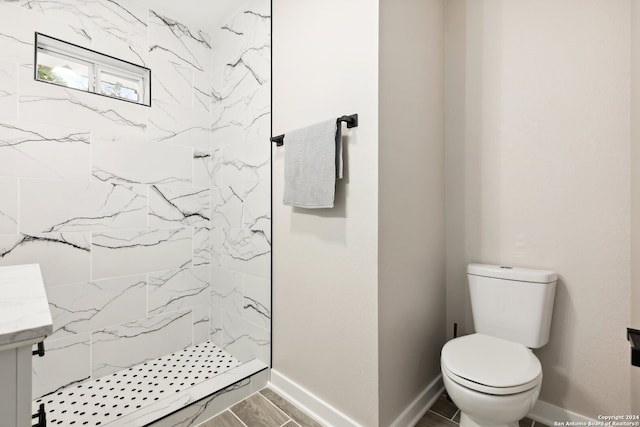 bathroom with tiled shower, vanity, and toilet