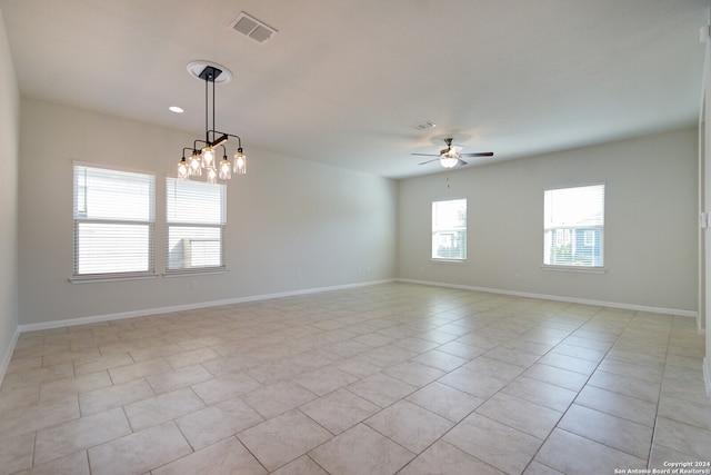 tiled spare room with ceiling fan with notable chandelier