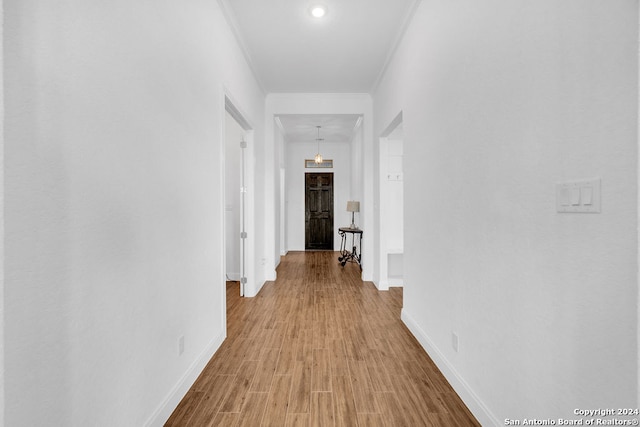 hall with ornamental molding and light hardwood / wood-style flooring