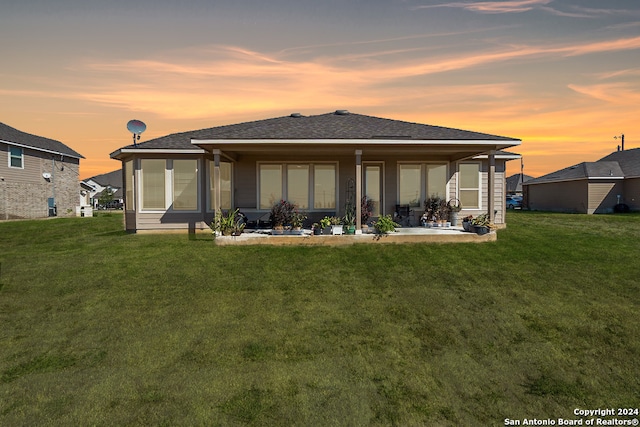 back house at dusk with a yard and a patio area