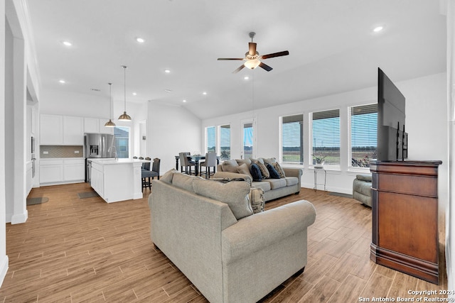 living room with ceiling fan, vaulted ceiling, and light hardwood / wood-style floors