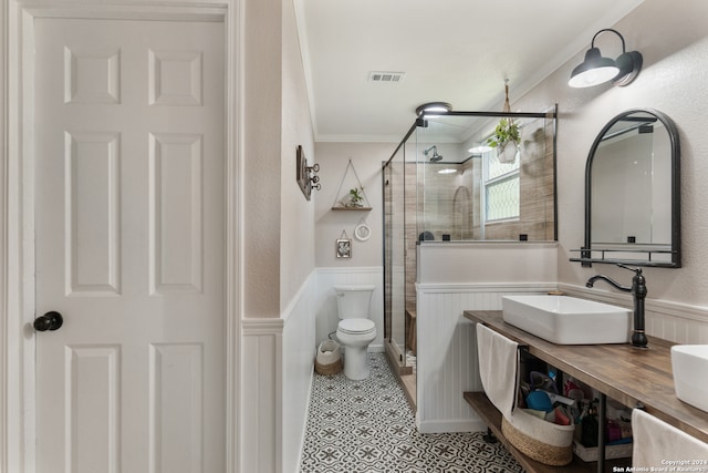 bathroom with vanity, crown molding, toilet, and a shower with door