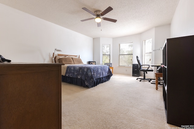 carpeted bedroom featuring ceiling fan and a textured ceiling