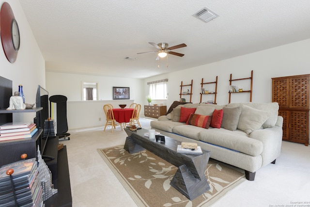 carpeted living room featuring a textured ceiling and ceiling fan