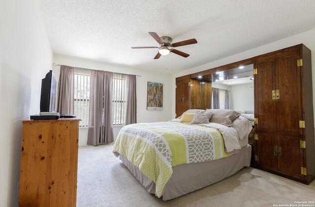 carpeted bedroom featuring ceiling fan and a textured ceiling