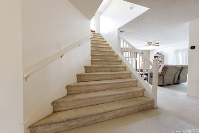 stairs featuring carpet flooring, a textured ceiling, and ceiling fan