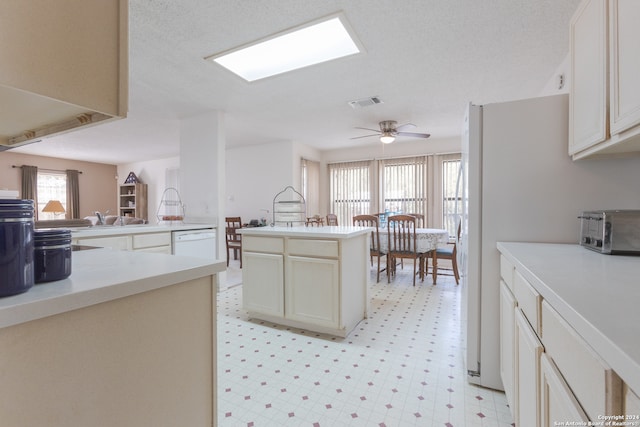 kitchen with kitchen peninsula, ceiling fan, dishwasher, cream cabinetry, and a kitchen island