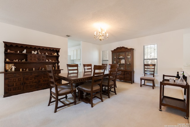 dining space with light carpet, a textured ceiling, and a chandelier