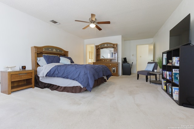 bedroom with ceiling fan, light colored carpet, and a textured ceiling