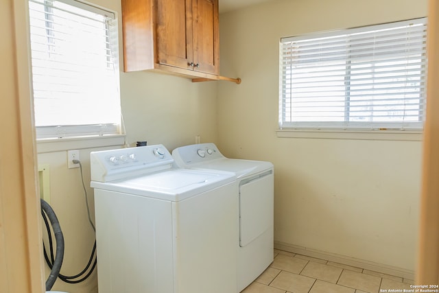 clothes washing area with a healthy amount of sunlight, separate washer and dryer, and cabinets