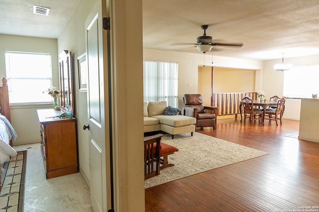 living room with ceiling fan with notable chandelier, hardwood / wood-style floors, and a wealth of natural light