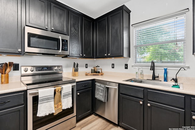 kitchen featuring stainless steel appliances, light wood-type flooring, and sink