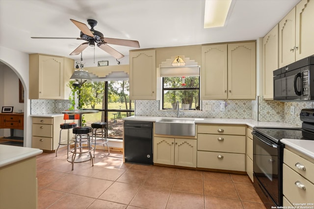 kitchen with black appliances, light tile patterned floors, cream cabinets, and ceiling fan