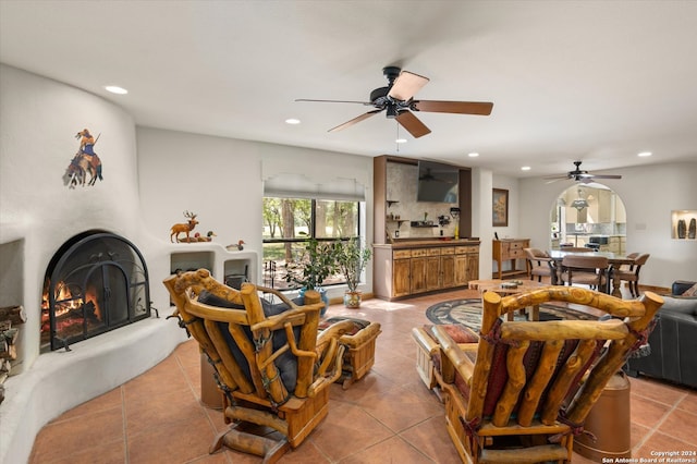 tiled living room featuring a large fireplace and ceiling fan