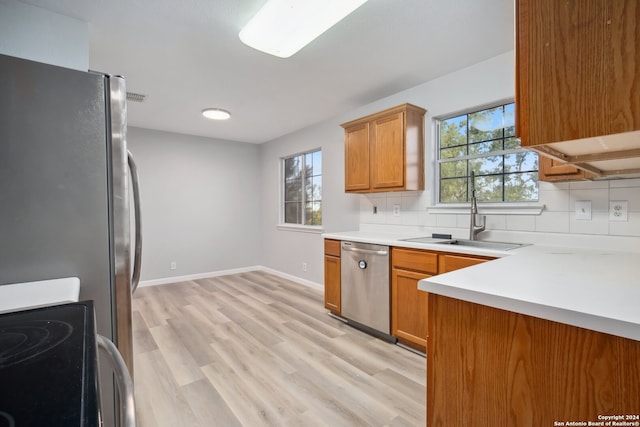 kitchen with appliances with stainless steel finishes, tasteful backsplash, light hardwood / wood-style floors, and plenty of natural light