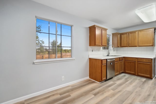 kitchen with stainless steel dishwasher, sink, decorative backsplash, and light hardwood / wood-style floors