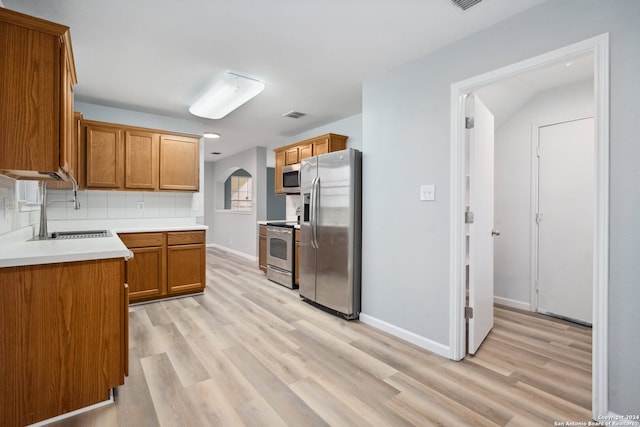 kitchen featuring appliances with stainless steel finishes, decorative backsplash, sink, and light hardwood / wood-style floors