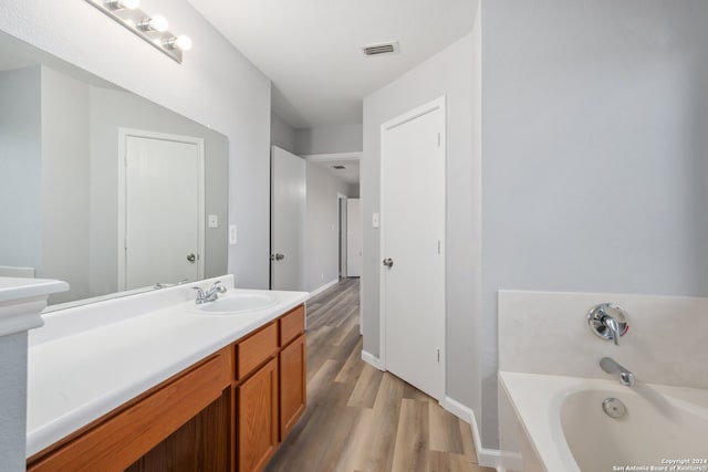 bathroom with vanity, hardwood / wood-style flooring, and a tub