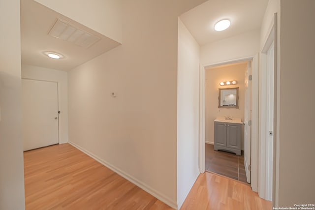 corridor featuring sink and light hardwood / wood-style flooring