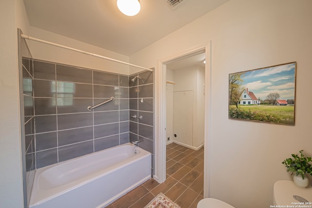 bathroom featuring tiled shower / bath and toilet