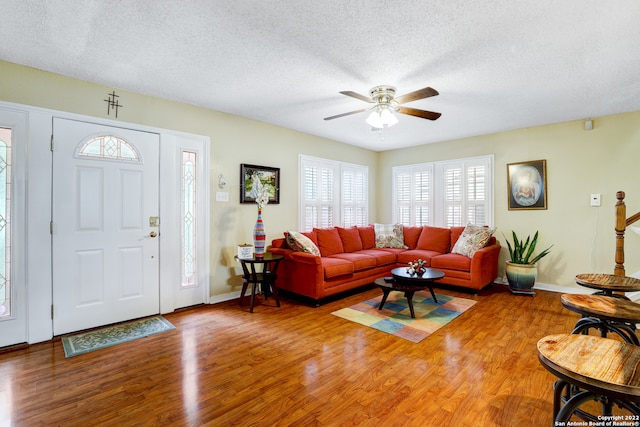 living room with ceiling fan, a textured ceiling, and hardwood / wood-style floors