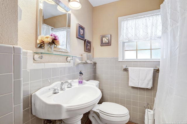 bathroom with sink, tile walls, and toilet