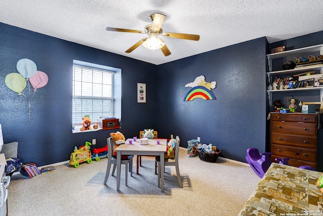 playroom featuring ceiling fan, carpet flooring, and a textured ceiling