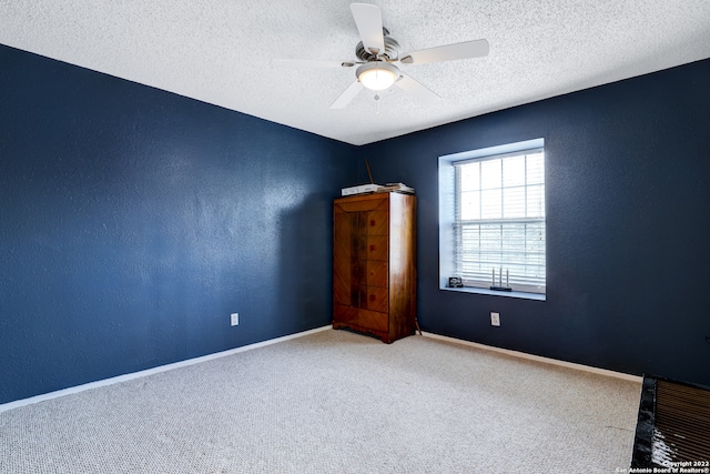 carpeted empty room with ceiling fan and a textured ceiling