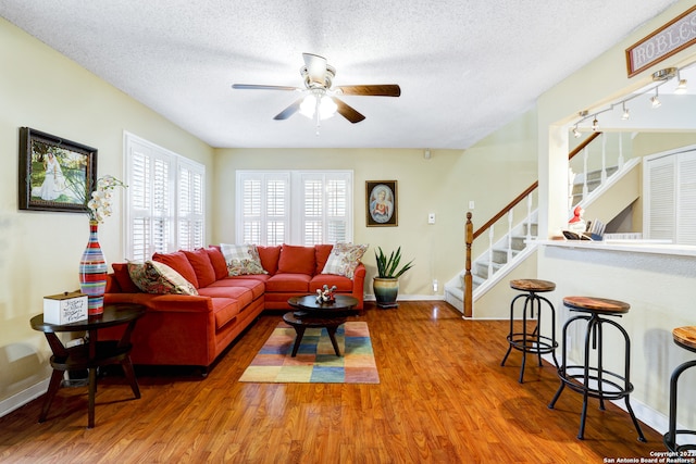 living room with a textured ceiling, hardwood / wood-style floors, and ceiling fan