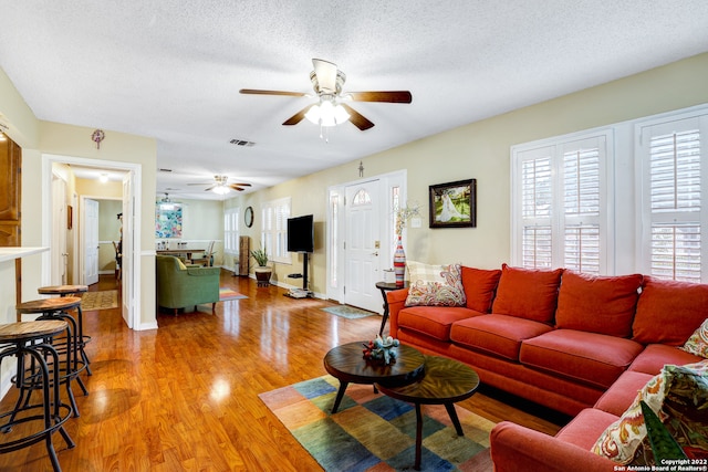 living room featuring ceiling fan, hardwood / wood-style floors, and a textured ceiling