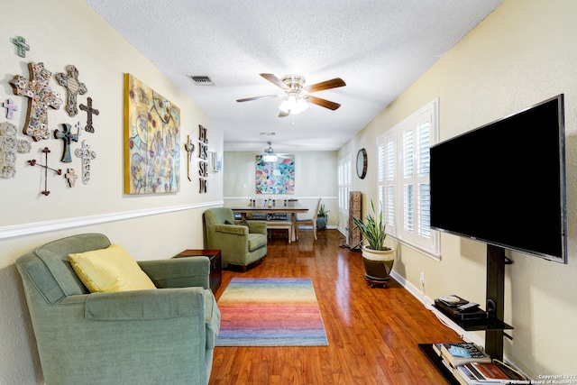 living room featuring a textured ceiling, hardwood / wood-style floors, and ceiling fan