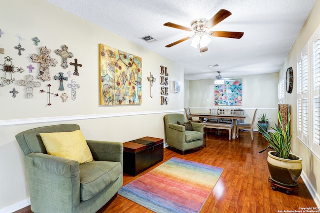 living area with a textured ceiling, ceiling fan, and hardwood / wood-style flooring