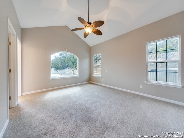 empty room with light carpet, lofted ceiling, ceiling fan, and a healthy amount of sunlight