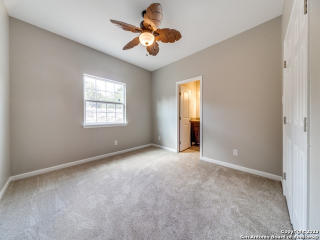 unfurnished bedroom with ceiling fan, light carpet, and ensuite bathroom