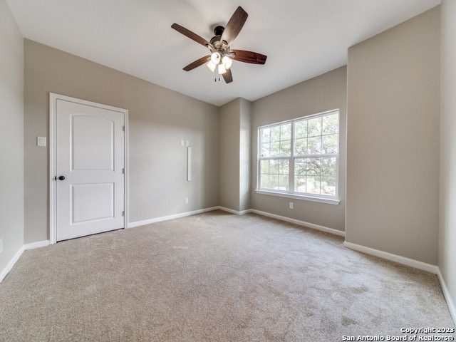 carpeted spare room with ceiling fan