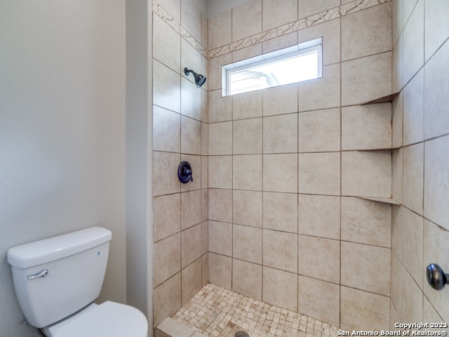 bathroom featuring a tile shower and toilet