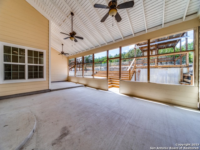 unfurnished sunroom featuring vaulted ceiling, ceiling fan, and a healthy amount of sunlight