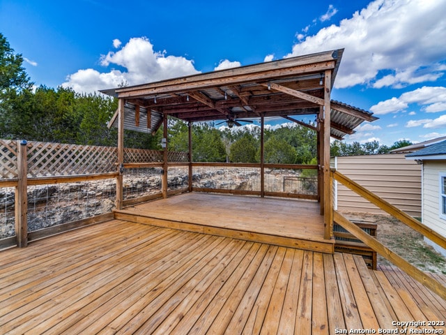 wooden deck with ceiling fan and a pergola