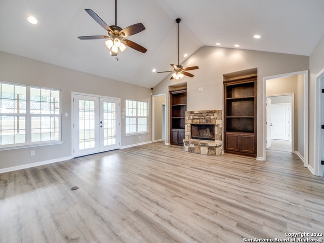 unfurnished living room featuring high vaulted ceiling, light wood-type flooring, ceiling fan, and a fireplace