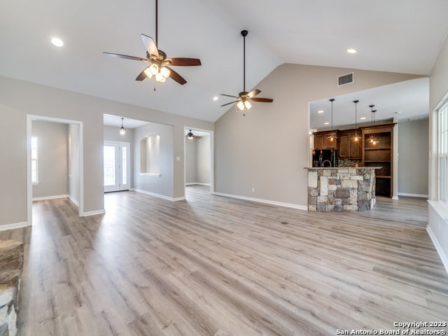 unfurnished living room with high vaulted ceiling, light hardwood / wood-style floors, and ceiling fan