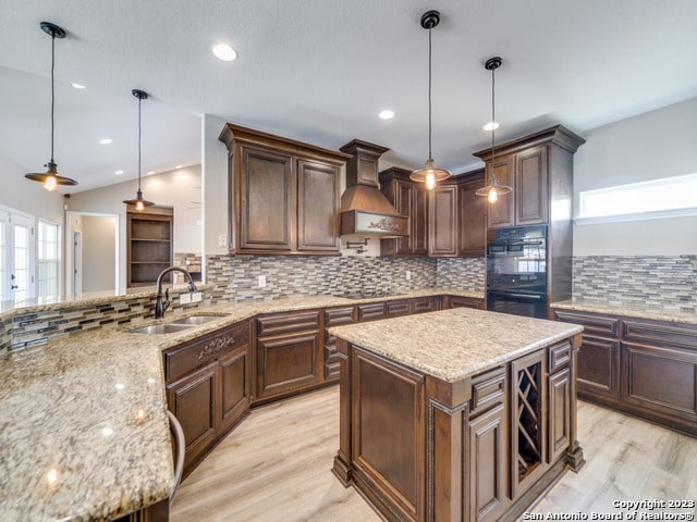 kitchen featuring a kitchen island, decorative light fixtures, custom range hood, and a healthy amount of sunlight