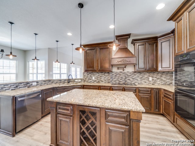 kitchen featuring black appliances, a wealth of natural light, hanging light fixtures, and a kitchen island