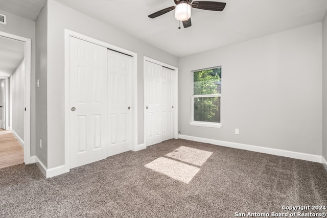 unfurnished bedroom with ceiling fan, two closets, and carpet flooring