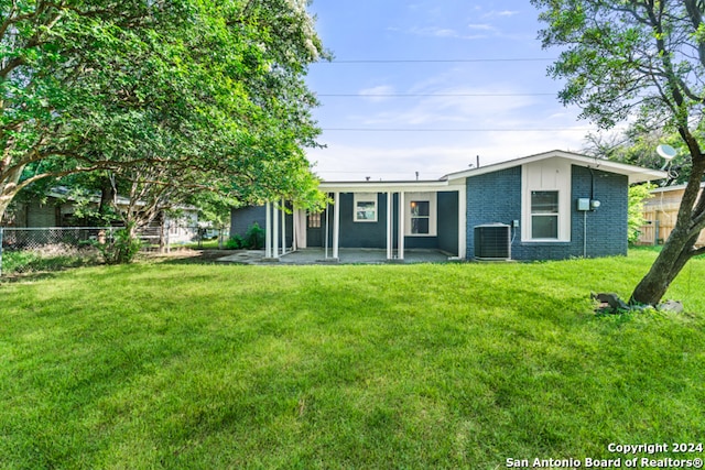 back of property featuring central AC unit, a patio area, and a yard